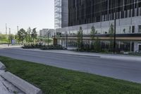 a city road lined with grass next to buildings on either side of it and a street sign near the road