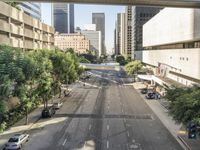 a view of some cars on a road in the city with buildings and trees on either side
