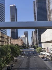 a view of some cars on a road in the city with buildings and trees on either side