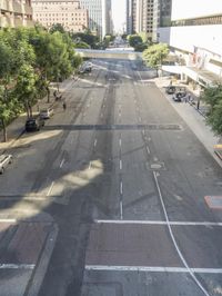 a view of some cars on a road in the city with buildings and trees on either side