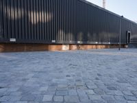 a brick building with glass windows and sidewalk leading to it and a black fire hydrant