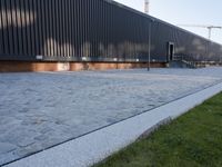 a brick building with glass windows and sidewalk leading to it and a black fire hydrant
