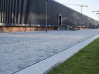 a brick building with glass windows and sidewalk leading to it and a black fire hydrant