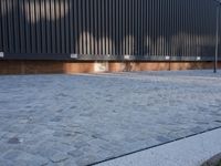 a brick building with glass windows and sidewalk leading to it and a black fire hydrant