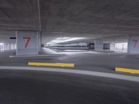 an empty parking garage with two numbered spaces in front of it on one side of the road