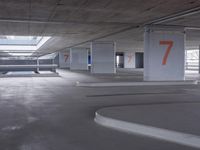 an empty parking garage with two numbered spaces in front of it on one side of the road