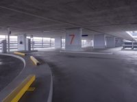 an empty parking garage with two numbered spaces in front of it on one side of the road