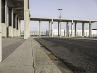 a picture of a very long building in the middle of nowhere with concrete structures and a parking lot in the background