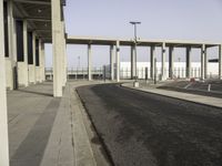 a picture of a very long building in the middle of nowhere with concrete structures and a parking lot in the background