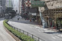 people walk along the side of a road by a market in a city area with no traffic