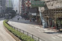 people walk along the side of a road by a market in a city area with no traffic