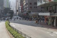 people walk along the side of a road by a market in a city area with no traffic