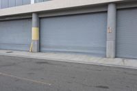 an industrial steel closed garage door is on the side of a street next to a large building