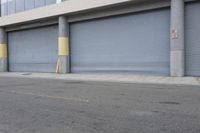 an industrial steel closed garage door is on the side of a street next to a large building