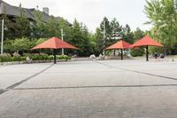 several empty benches and umbrellas on a brick street with trees in the background in the city park