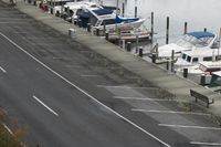 a long road going by a marina with boats in the water on it and people walking along the walkway