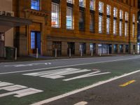 a man walking through an empty street in front of a building at night, with stop sign painted on the road