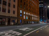 a man walking through an empty street in front of a building at night, with stop sign painted on the road