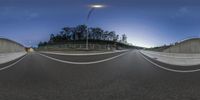 a 360 - view of a wide city road with traffic lights at night in the distance