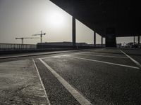 a view of a construction site with traffic lights in the middle of the road under an overpass