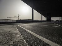 a view of a construction site with traffic lights in the middle of the road under an overpass