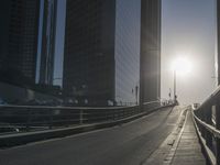 a road in the middle of a city with the sun setting on it's horizon