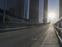 a road in the middle of a city with the sun setting on it's horizon
