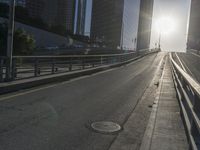 a road in the middle of a city with the sun setting on it's horizon