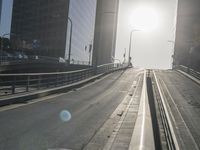 a road in the middle of a city with the sun setting on it's horizon
