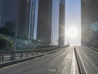 a road in the middle of a city with the sun setting on it's horizon