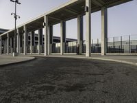 an empty road lined with lots of pillars and pillars are on either side of the building