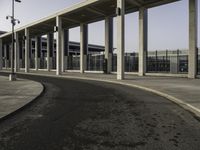 an empty road lined with lots of pillars and pillars are on either side of the building