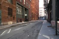 an alley way with people walking along and two cars in the street and buildings behind
