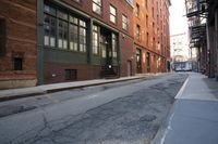 an alley way with people walking along and two cars in the street and buildings behind