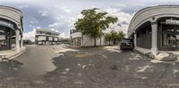 360 view photo of a building across a road from another building and a parking lot