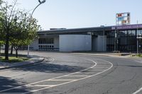 a road with cars and two signs in front of an airport with trees on either side