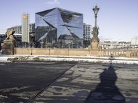 the shadow of a person riding a bicycle in a street in front of a tall glass building