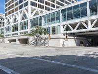 people are walking along the sidewalk near an outdoor parking garage and trees as well as a bus stop light