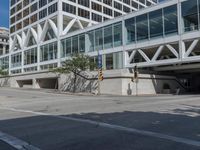 people are walking along the sidewalk near an outdoor parking garage and trees as well as a bus stop light