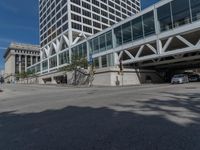 people are walking along the sidewalk near an outdoor parking garage and trees as well as a bus stop light