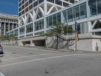 people are walking along the sidewalk near an outdoor parking garage and trees as well as a bus stop light