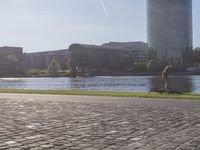a person sitting on a bench next to a large body of water with a building in the background