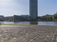 a person sitting on a bench next to a large body of water with a building in the background