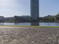 a person sitting on a bench next to a large body of water with a building in the background