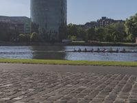 a person sitting on a bench next to a large body of water with a building in the background