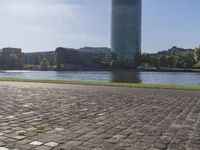 a person sitting on a bench next to a large body of water with a building in the background