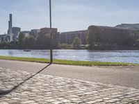 a person sitting on a bench next to a large body of water with a building in the background