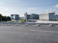 a wide road with buildings in the background and blue sky above it and some wires