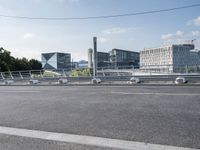 a wide road with buildings in the background and blue sky above it and some wires