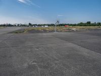 a basketball hoop sits on the corner of an empty parking lot where players are standing